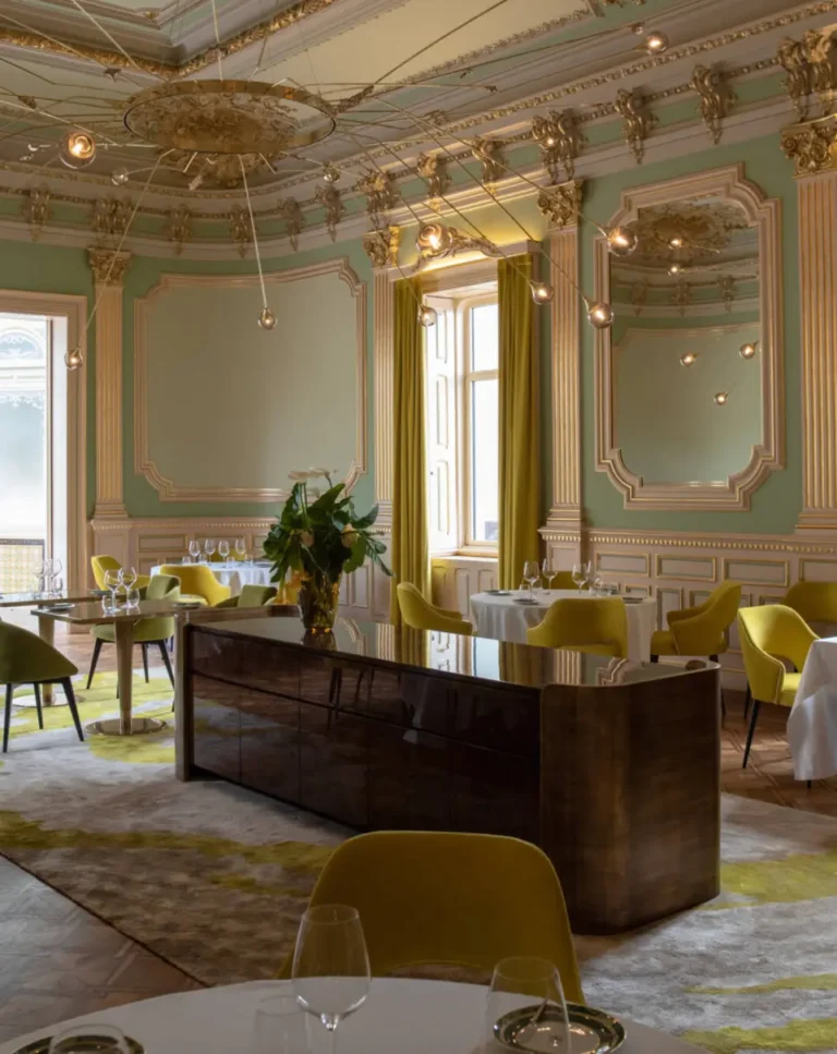 Salle de restaurant chic avec plafond ornementé et chaises jaunes