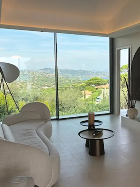 Salon lumineux avec baie vitrée offrant une vue panoramique sur la nature