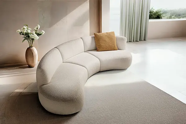 Canapé arrondi en tissu blanc avec coussin décoratif.