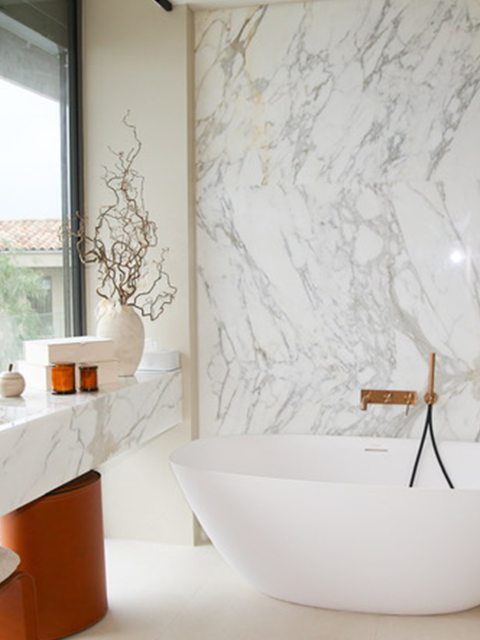 Salle de bain luxueuse avec baignoire îlot et marbre blanc.