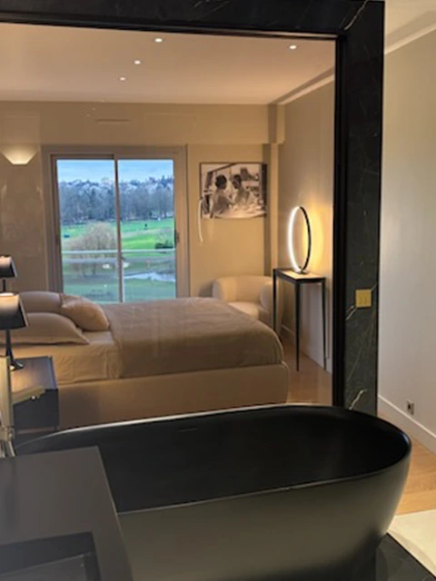 Salle de bain contemporaine avec miroir rond et meuble noir.