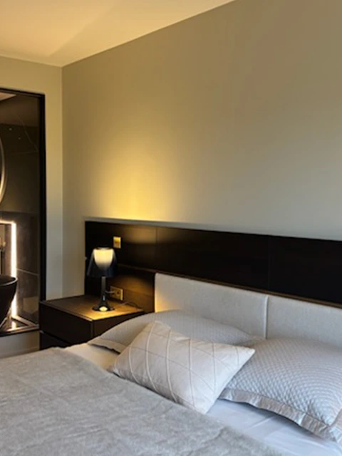 Chambre moderne avec tête de lit et éclairage tamisé.