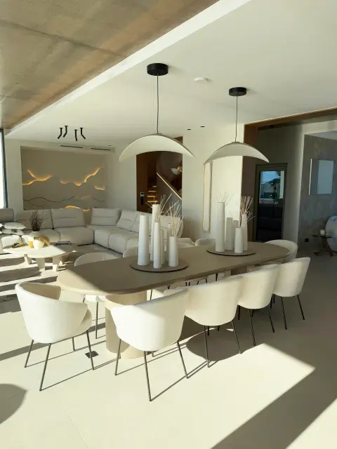 Salle à manger lumineuse avec table en bois et chaises blanches.